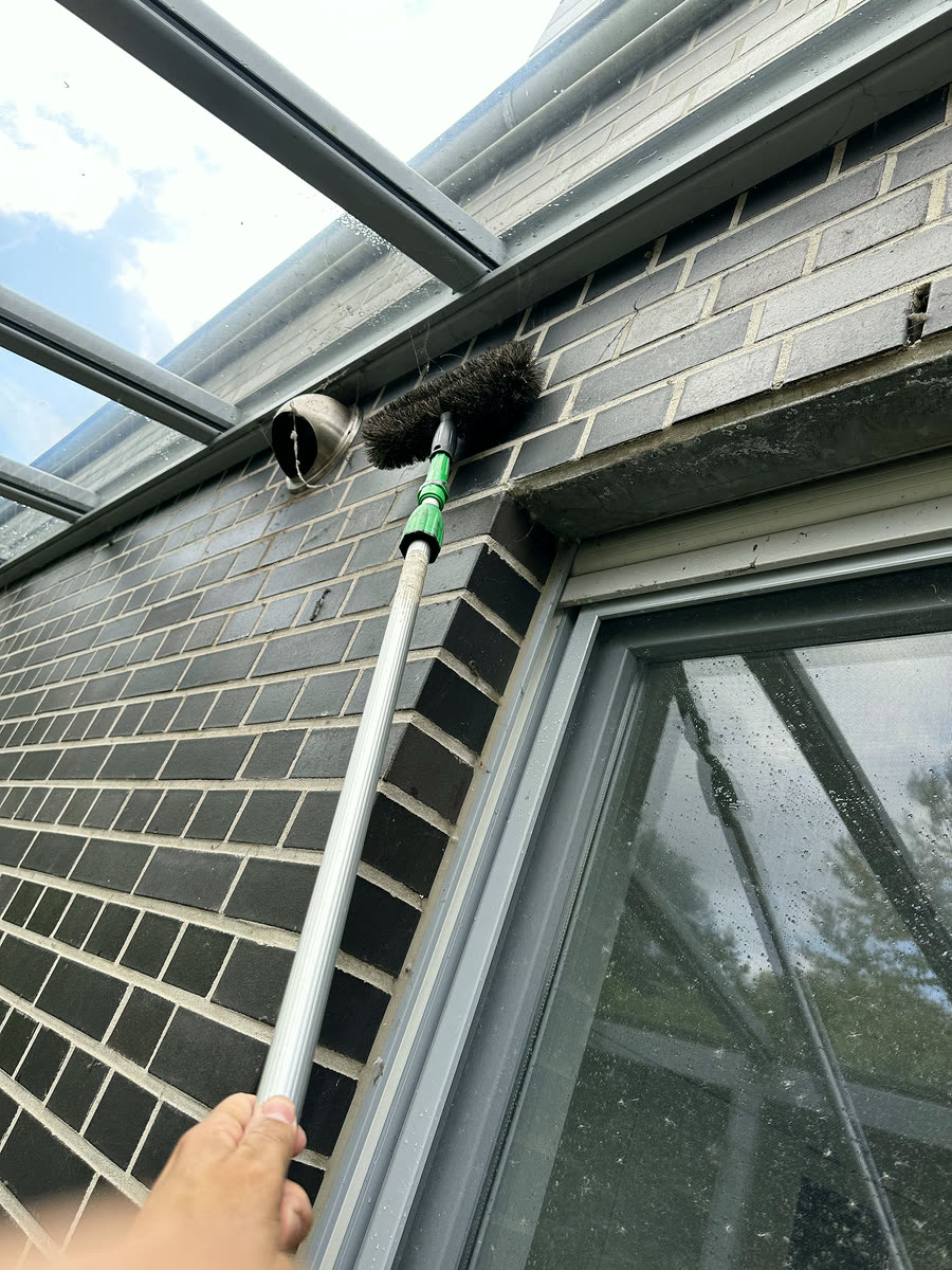 Glasdach eines Wintergartens wird mit Bürste gereinigt – Gebäudereinigung in Olfen